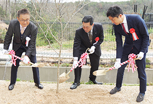 記念植樹を行う岡崎雅廣社長、奥田正和町長、河島伸浩社長（左から）