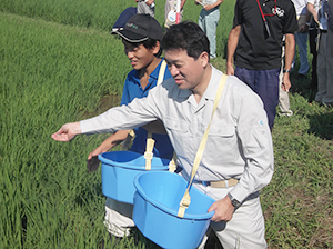 農業大学校の農地で施肥する泉田裕彦知事（右）