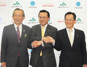笑顔で握手を交わす、左から横本正樹組合長、國廣喜和武社長、高田幸典町長