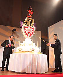 特大バースデーケーキにろうそくをともす毅会長（左）と祥行社長