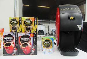 新発売の「ブラック」ステイック（左）、「ゴールドブレンド　アイスコーヒー」（中）と「バリスタ」マシン（右）