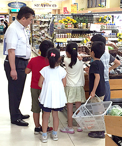 野菜・果物を選ぶ「お買い物ゲーム」に挑んだ児童たち。左は村越弘之店長（東急ストアつくし野店で）