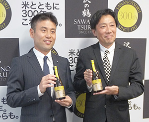 新商品を手にする西村隆沢の鶴代表取締役社長（左）と小丸和弘NPO法人梅田ミツバチプロジェクト代表