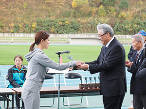 女子フルマラソンの優勝者へ日東アリマン杯を授与する斎藤弥寿夫社長（右）