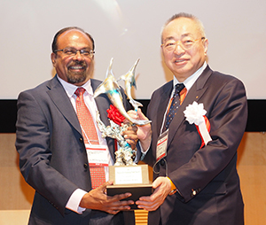 池田弘理事長（右）から正賞のシュプリンゲンが授与される大賞のジェヤクマール・ヘンリー氏
