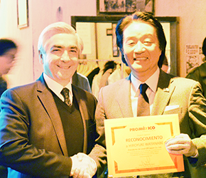 表彰状を手に持つ渡邊弘之社長（右）とカルロス・アルマーダ大使