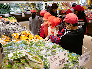 「買物ゲーム」で指定金額内で必要な食材を選ぶ児童たち（スーパーアルプスはざま店で）